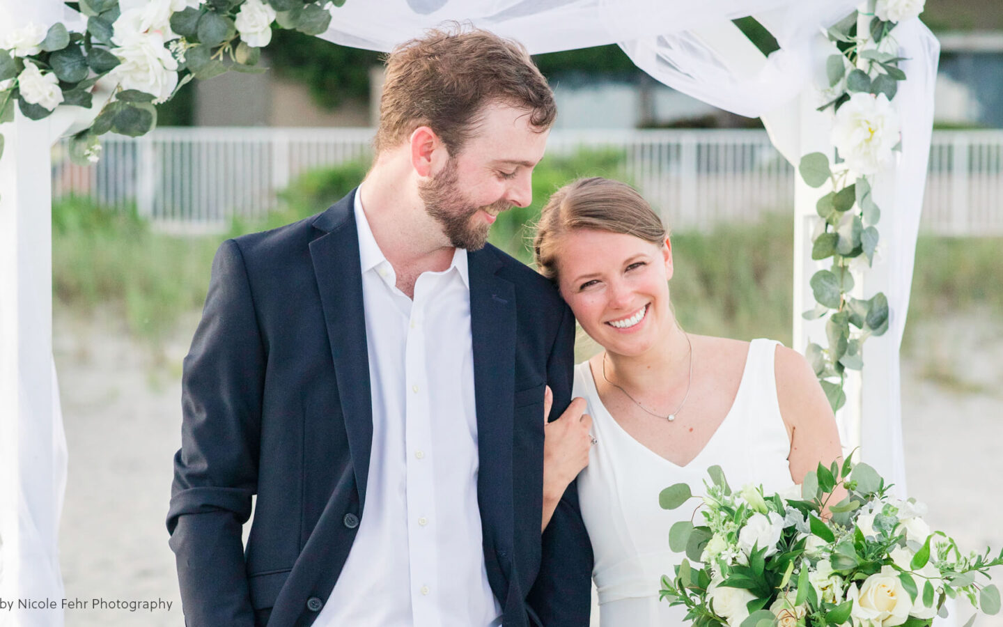 smiling bride with bouquet clutching groom's arm
