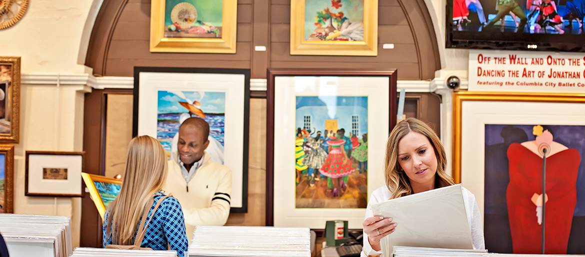 People browsing artwork and prints inside a colourful art gallery.