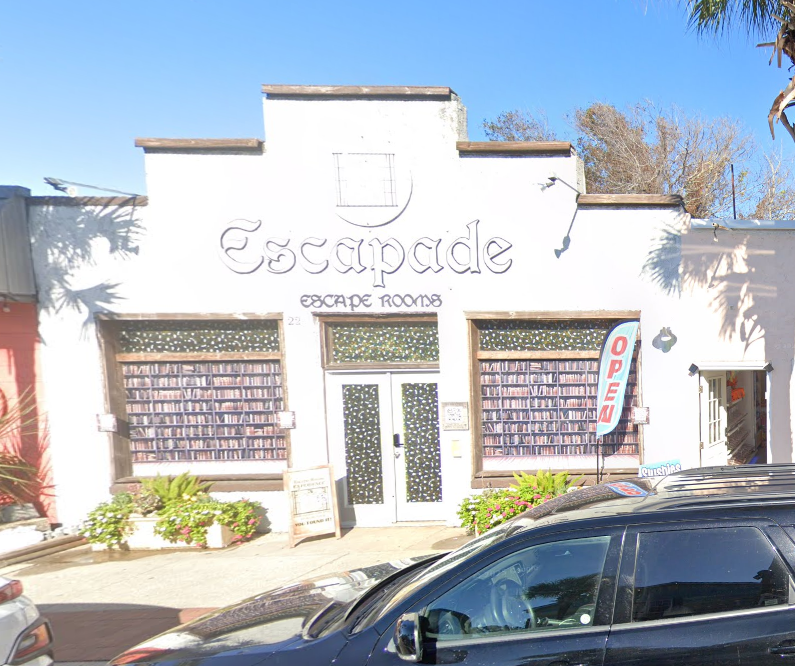 Exterior of Escapade Escape Rooms with decorative window displays and an open sign beside the entrance.