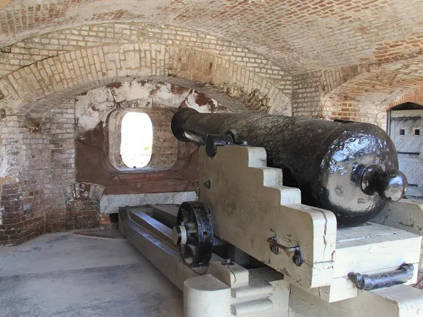 Historic cannon displayed inside a brick fort casemate.